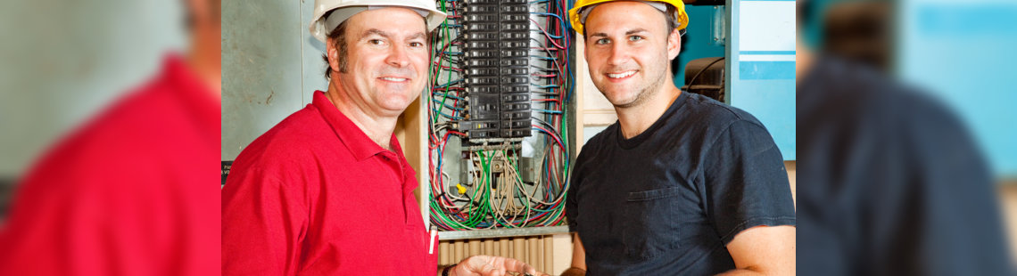 two electricians working on breaker panel